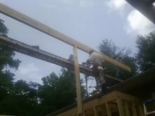 Carpenter setting a ridge beam over a new addition frame — Ice Dam Removal by Roofing Brothers in Biggs