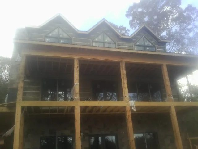Dormers and porch framing on a large log home under construction — Roof Coating work by our crew in Biggs