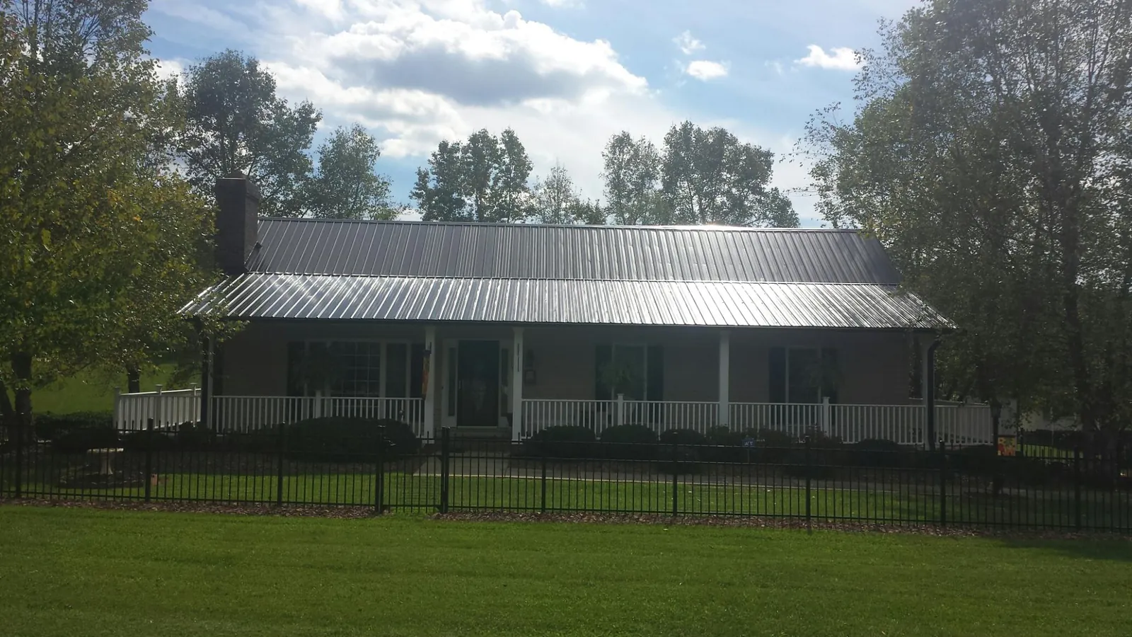 Gray metal roof on a brick ranch with a full width front porch — Gutter Guard Installation work by our crew in Biggs