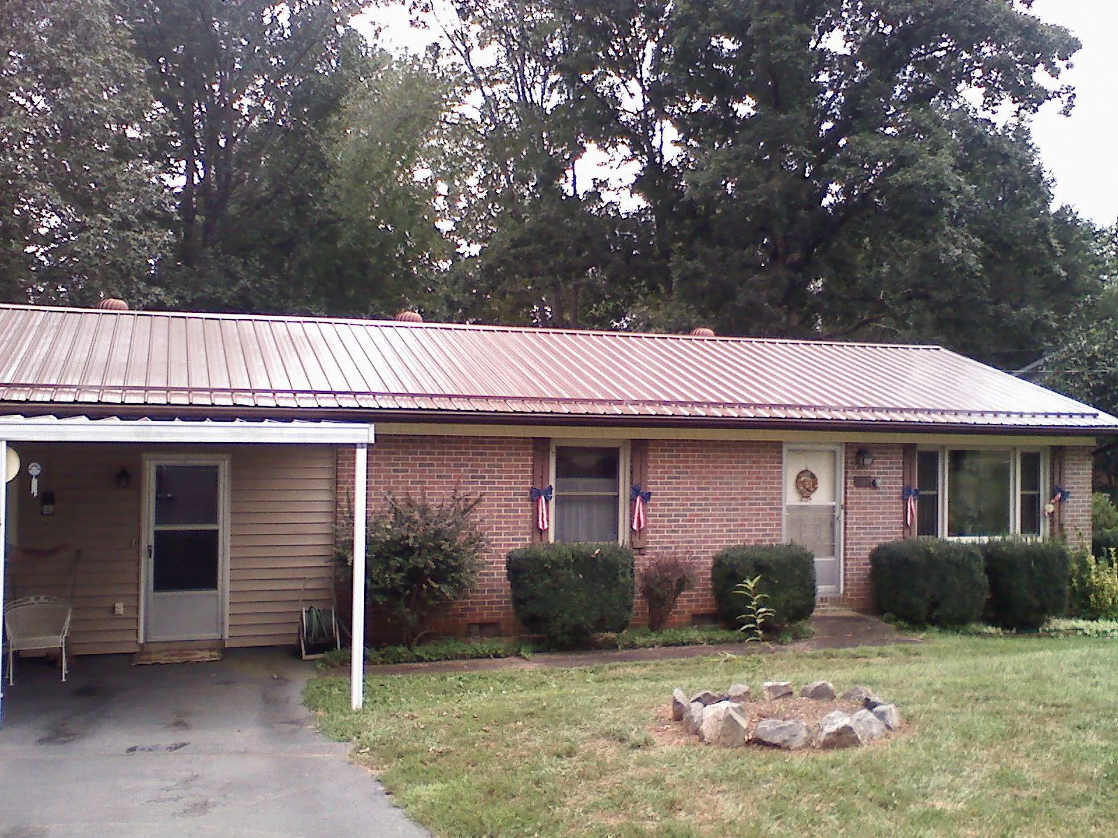 Bronze metal roof and carport on a brick ranch home — Roof Repair work by our crew in Biggs