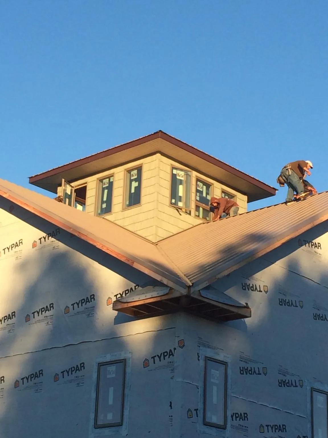 Roofers working around a rooftop cupola on a new metal roof at sunset — Roof Waterproofing in Biggs by Roofing Brothers